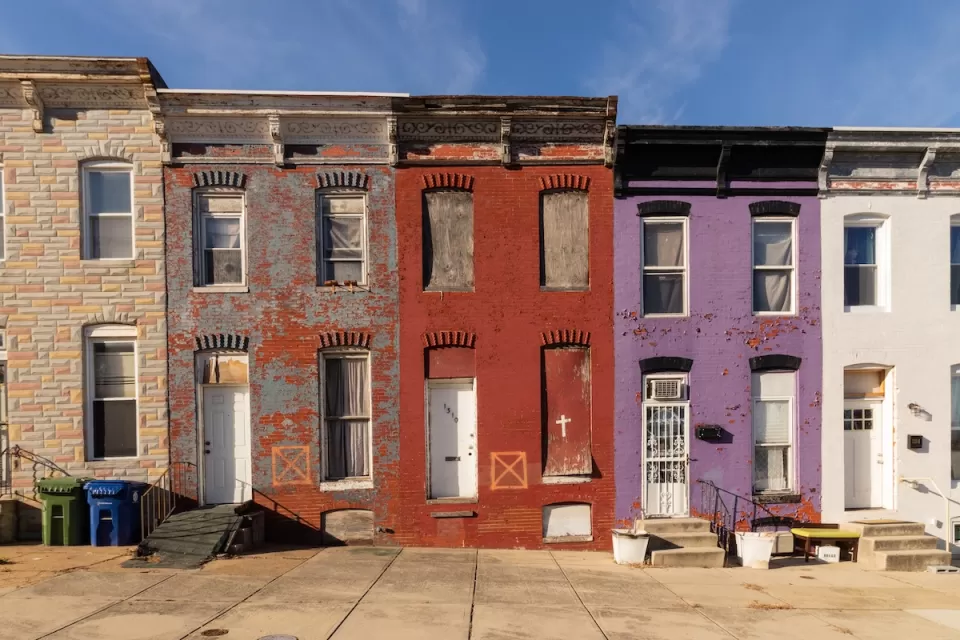 Row of colorful boarded-up brick two-story townhomes in baltimore, Maryland.